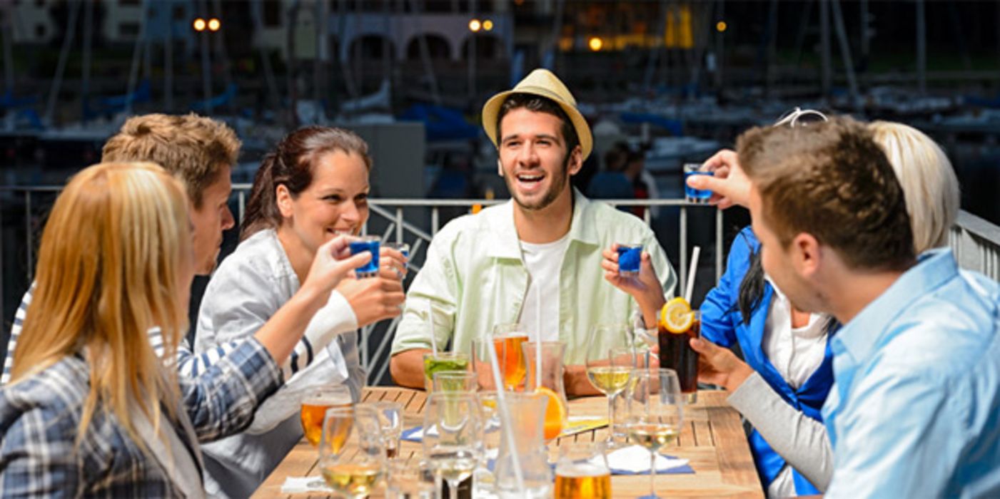 Gesellige Runde junger Menschen sitzt an einem Tisch.