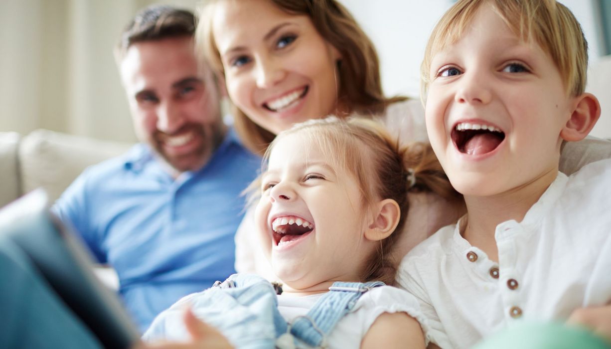 Familie mit zwei Kindern, sitzt zusammen auf dem Sofa. 