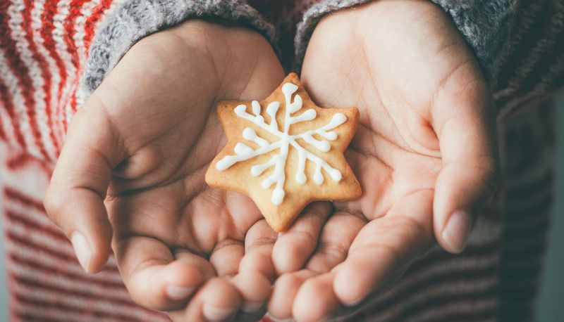 Kinderhand mit verziertem Weihnachtsplätzchen.