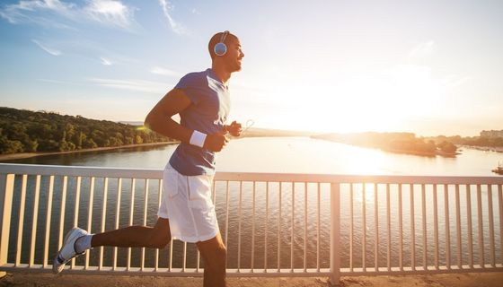 Ein jüngerer Mann joggt im Sommer über eine Brücke.