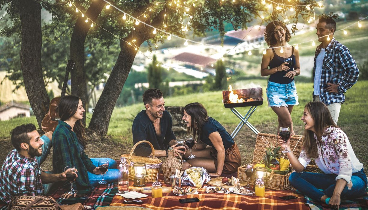 Gruppe von Freunden draußen auf einer Picknickdecke.