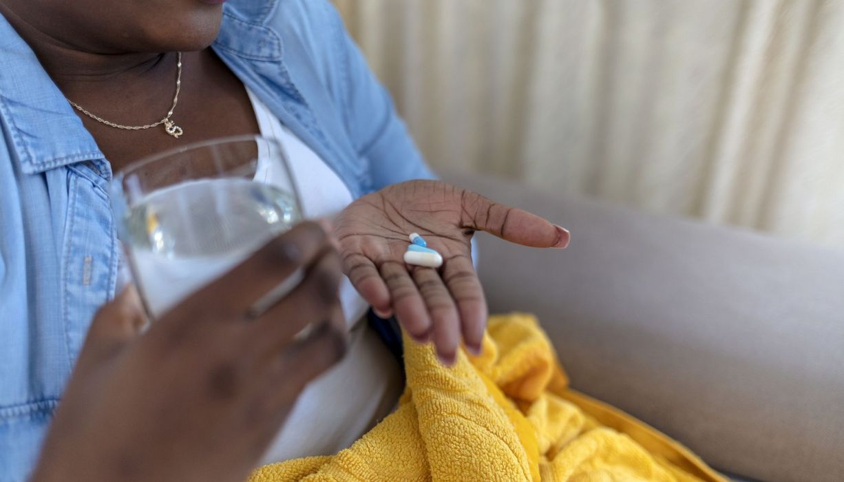 Übergewichtige Frau mit drei Tabletten in der Hand.