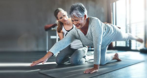 Ältere Frau, macht eine Yoga-Übung in der Reha.