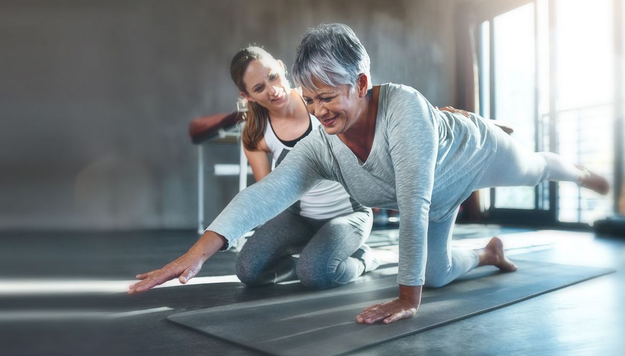 Ältere Frau, macht eine Yoga-Übung in der Reha.