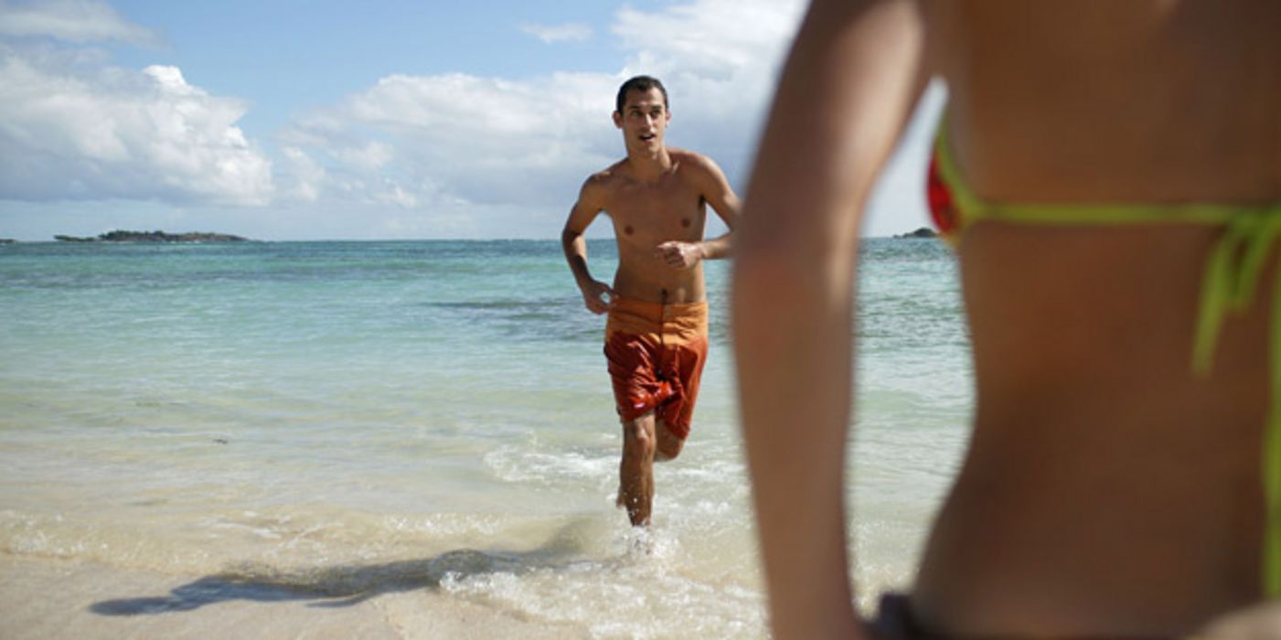 Junger Mann joggt am Strand.