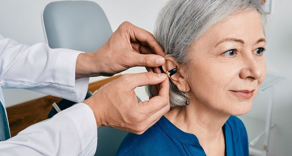 Ältere Frau, bekommt ein Hörgerät eingesetzt.