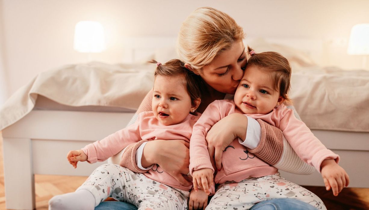 Mutter mit Zwillingsbabys auf ihrem Schoß.