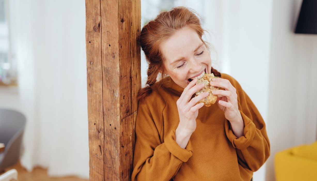 Junge Frau, beißt in ein Brot.