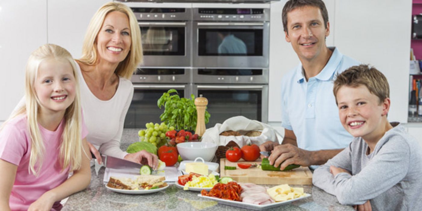 Familie sitzt am Tisch und isst Obst und Gemüse.