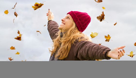 Frau mit Mütze im Herbstwald.