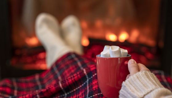 Frau, liegt auf der Couch und trinkt Kakao mit Marshmallows.