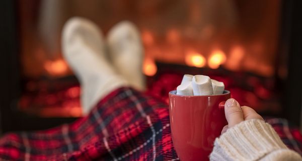 Frau, liegt auf der Couch und trinkt Kakao mit Marshmallows.