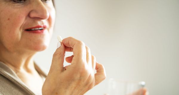 Ältere Frau, nimmt eine Tablette.