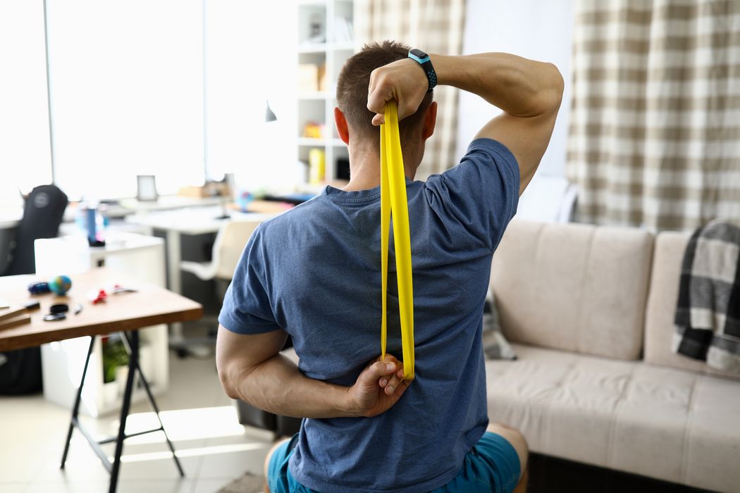 Mann, mit einem Fitnessband am Arbeitsplatz.