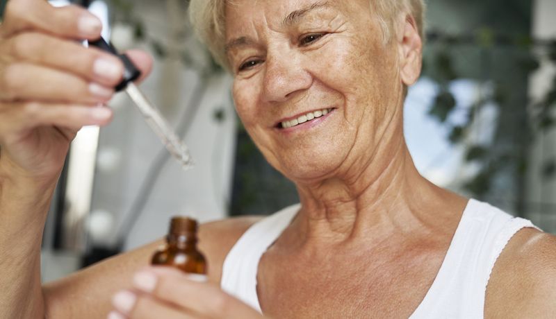 Ältere Frau mit einem Hautserum, behandelt ihre trockene Haut.