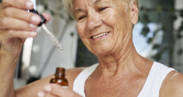 Ältere Frau mit einem Hautserum, behandelt ihre trockene Haut.