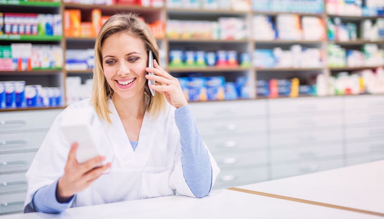 Freundliche Apothekerin telefoniert mit einem Kunden.