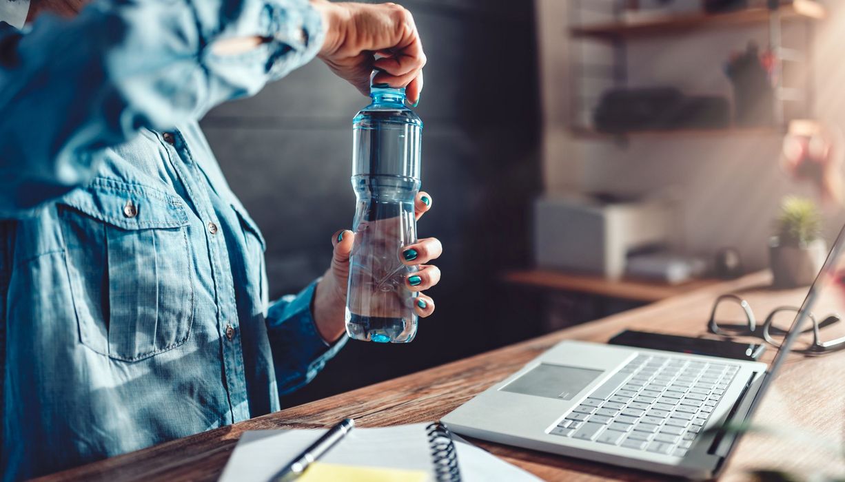 Frau öffnet Trinkflasche im Büro.