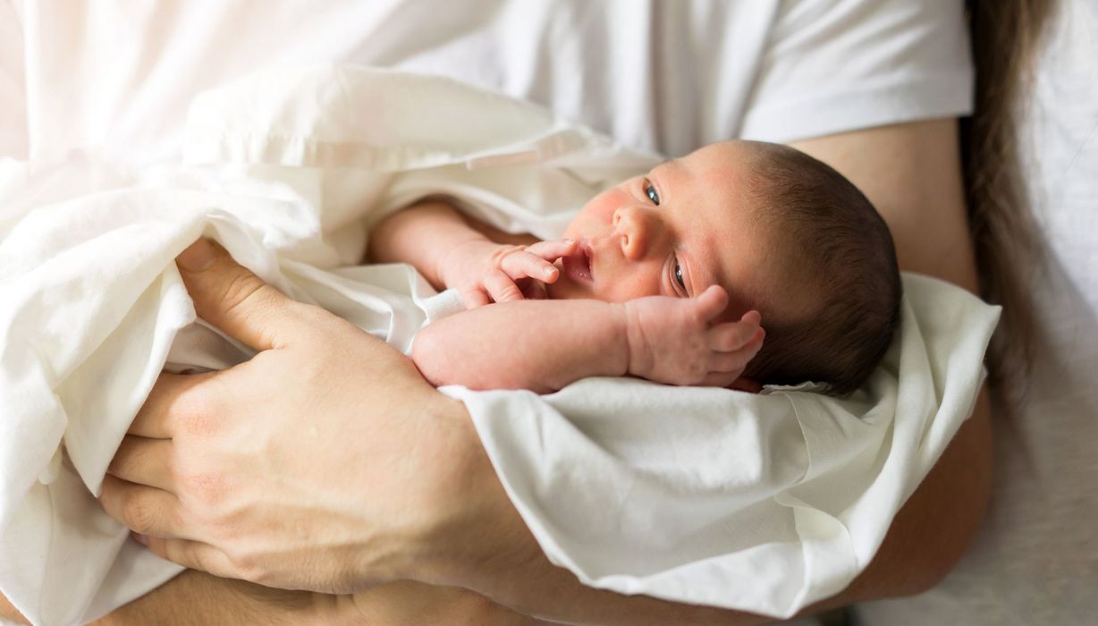 Mutter, hält neugeborenes Baby im Arm.