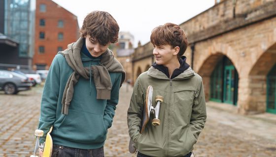 ZWei Teenager-Jungs mit Skateboards unter dem Arm.