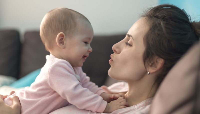 Baby, liegt bei Mama auf der Brust und lacht.