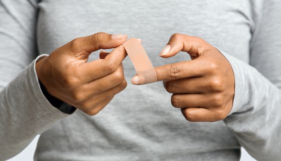 Eine Frau klebt sich ein Pflaster auf den Finger.