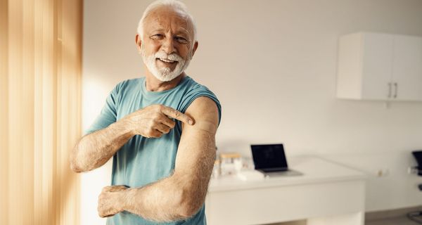 Mann, zeigt auf ein Pflaster auf seinem Arm.