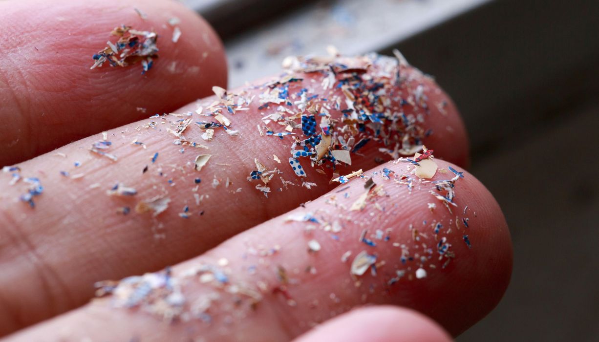 Winzige Plastikteilchen auf Fingern.