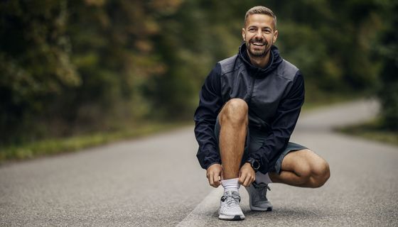 junger Mann pausiert in der Hocke beim Jogging