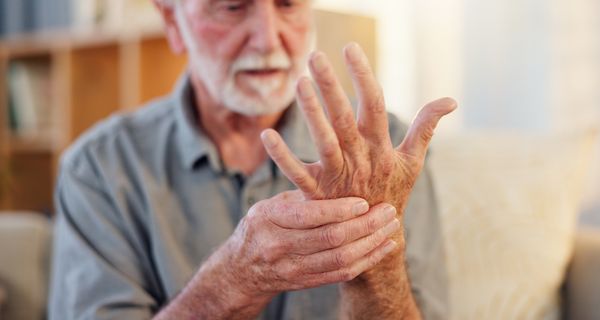 Mann, hält sich eine Hand.