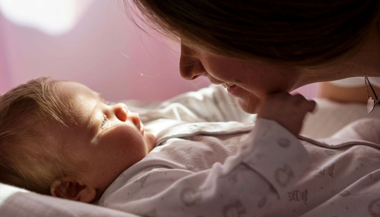 Junge Frau, beugt sich über ihr Baby und lächelt.