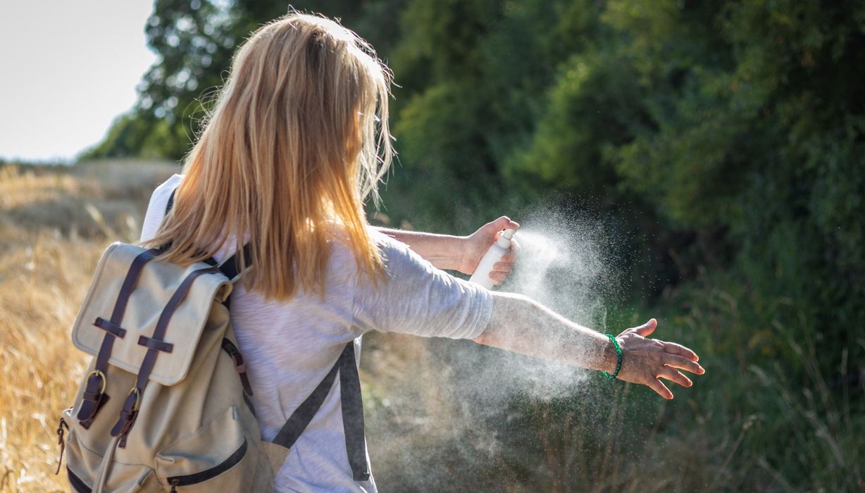 Blonde Frau, nutzt ein Insektenschutz-Spray.