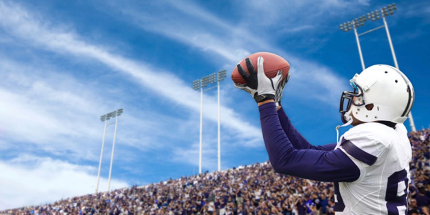 American Football-Spieler im Stadion fängt einen Football