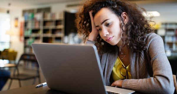 Junge Frau, sitzt vor einem Laptop.