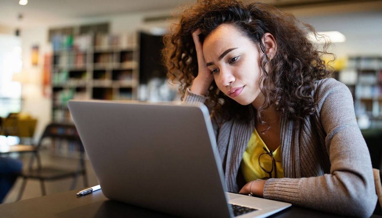 Junge Frau, sitzt vor einem Laptop.