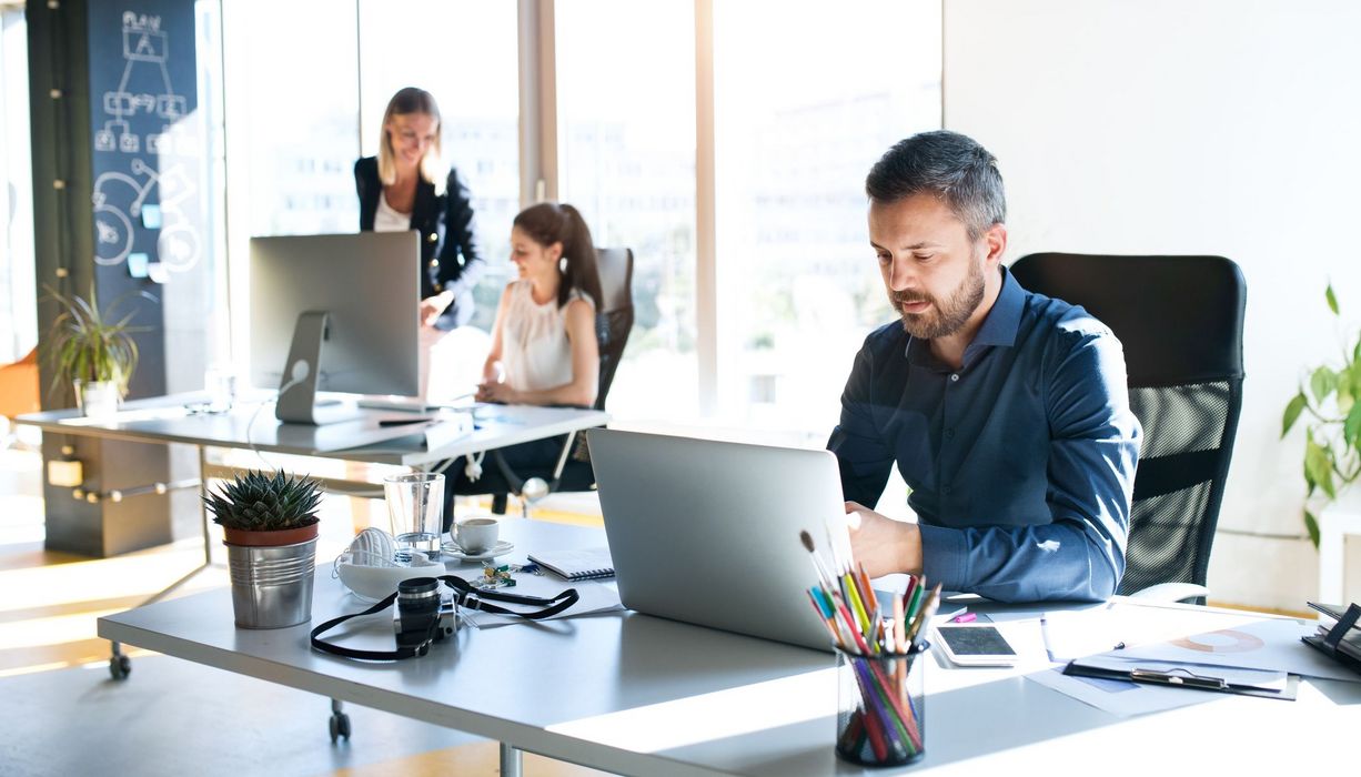 Mehrere Menschen arbeiten in hellem Büro.