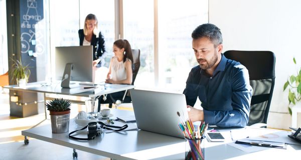 Mehrere Menschen arbeiten in hellem Büro.