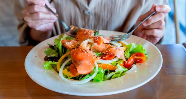 Frau, isst einen Salat mit Lachs.