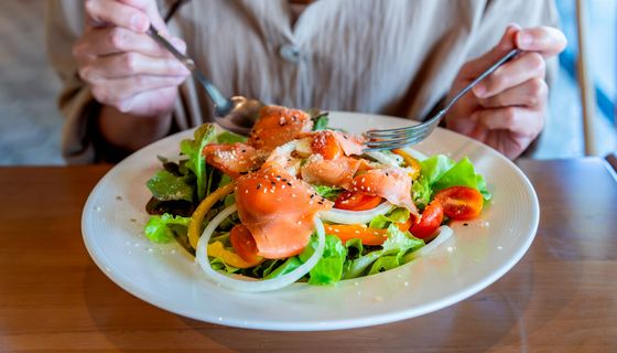 Frau, isst einen Salat mit Lachs.