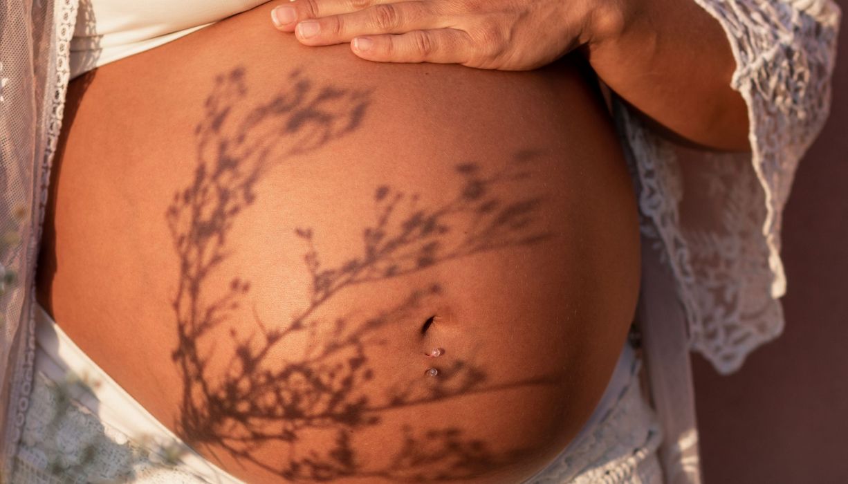 Schwangere Frau hält Hand auf ihren Bauch