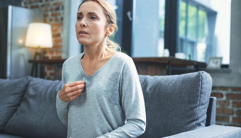 Frau mit Schweißausbrüchen und gequältem Blick.