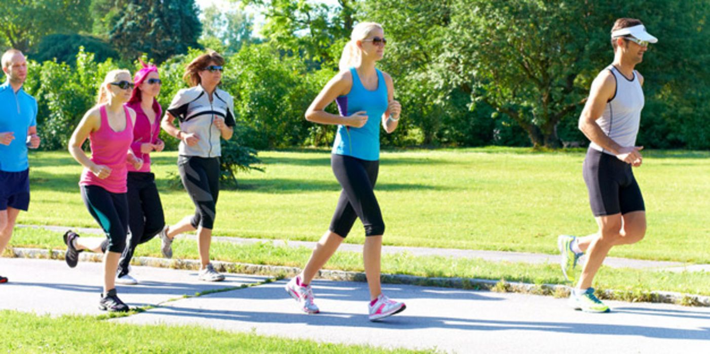 Gruppe (in den 30ern) in leichter Kleidung beim Joggen im Park