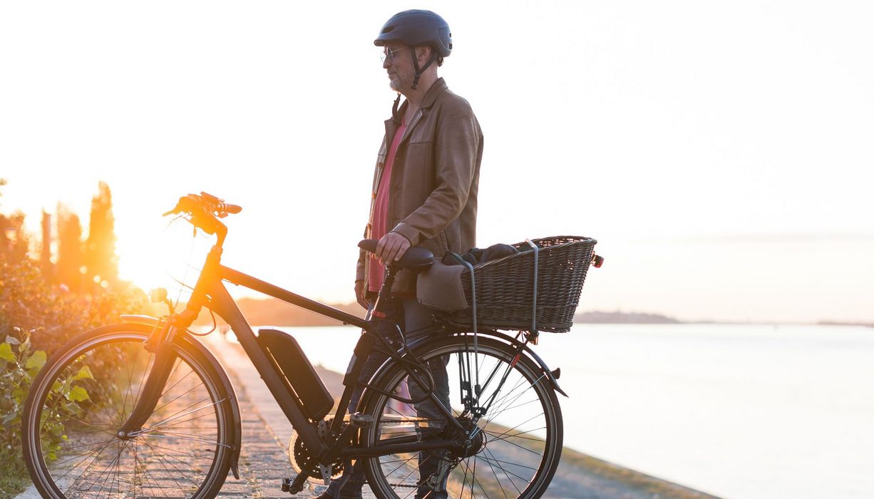 Älterer Mann, steht neben seinem E-Bike.