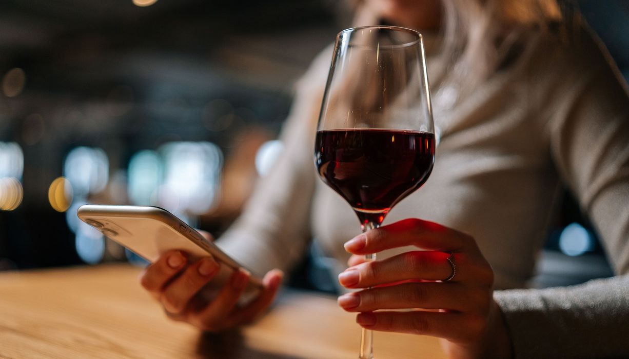 Frau, hält ein Glas Wein in der Hand.