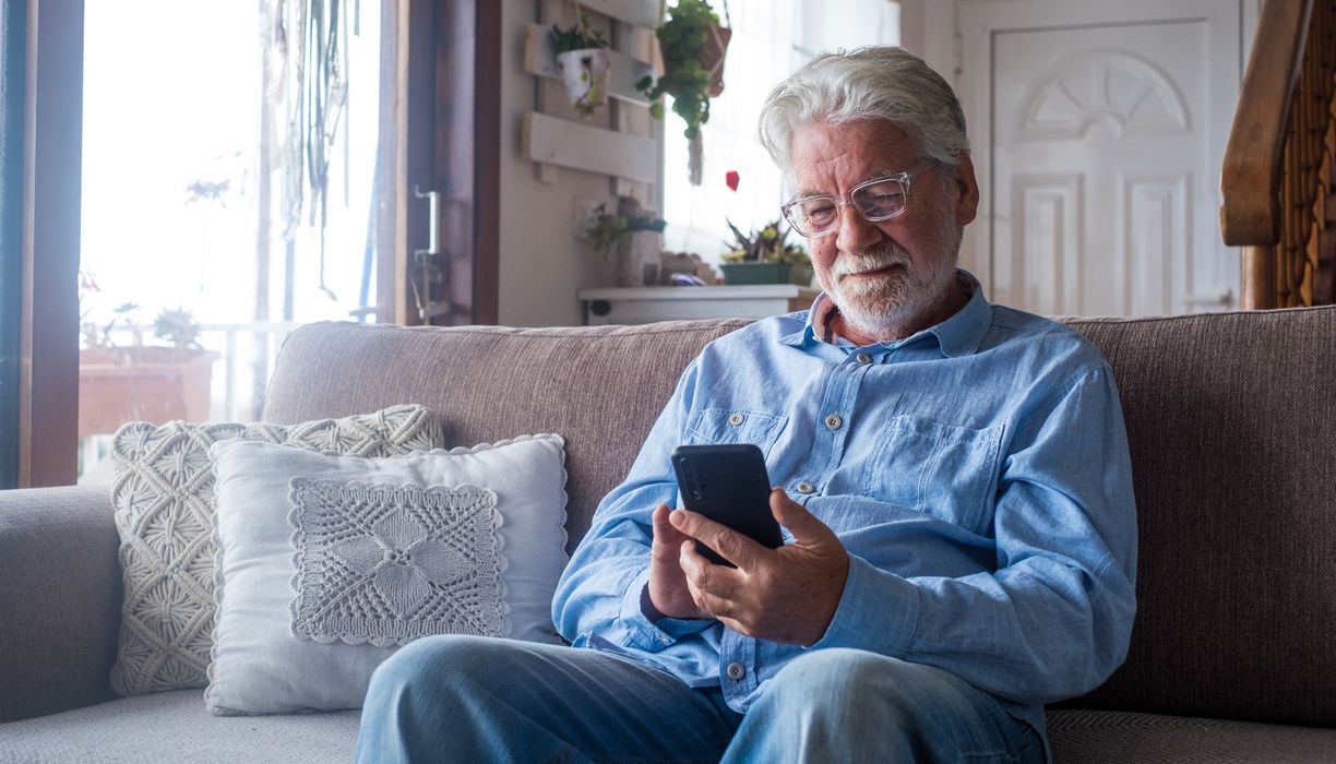 Senior, schaut auf sein Smartphone.