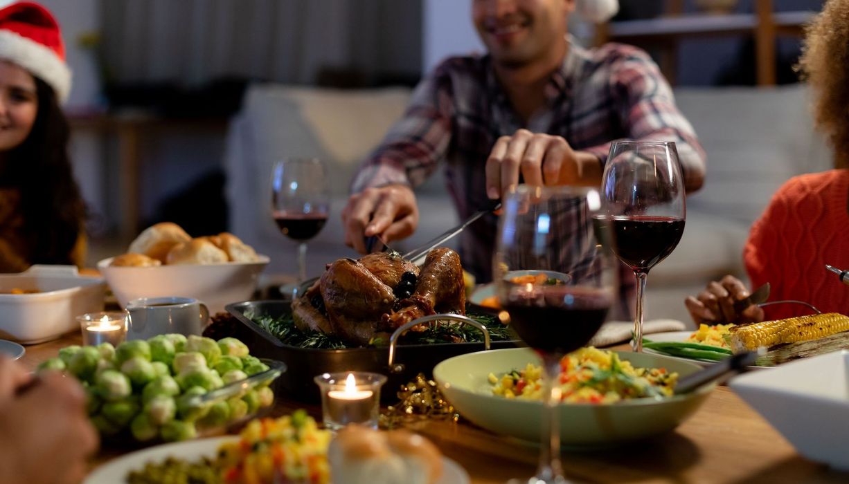 Esstisch mit Gänsebraten, Wein und Rosenkohl.