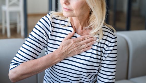 Frau, hält eine Hand an ihre Brust.