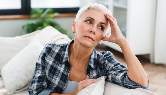 Frau mit kurzen blonden Haaren sitzt auf einem Sofa.