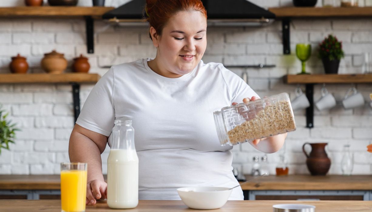 Übergewichtige Frau, bereitet sich ein Müsli zu.