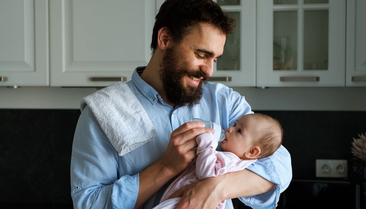 Vater, füttert sein Baby mit einer Flasche.